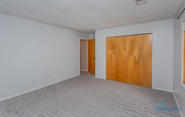 unfurnished bedroom featuring carpet floors, a textured ceiling, and a closet