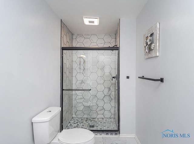 bathroom featuring a shower with door and toilet