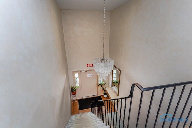 stairs featuring a high ceiling and a notable chandelier