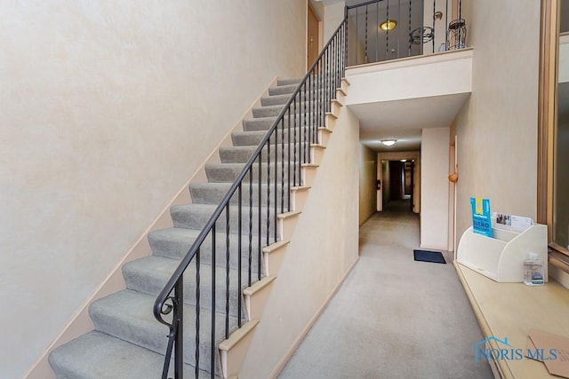 stairway featuring a towering ceiling and carpet flooring