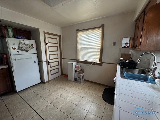 kitchen featuring sink, light tile patterned floors, backsplash, tile countertops, and white fridge