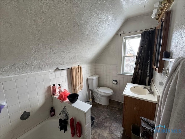 bathroom featuring tile walls, vanity, a textured ceiling, a tub to relax in, and toilet