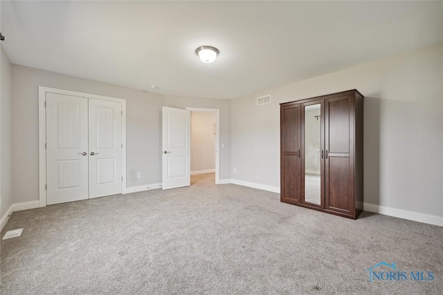 unfurnished bedroom with light carpet and a closet