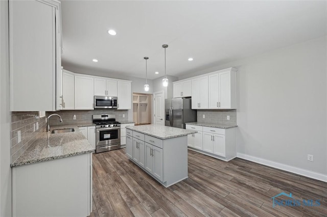 kitchen featuring sink, hanging light fixtures, a kitchen island, stainless steel appliances, and white cabinets