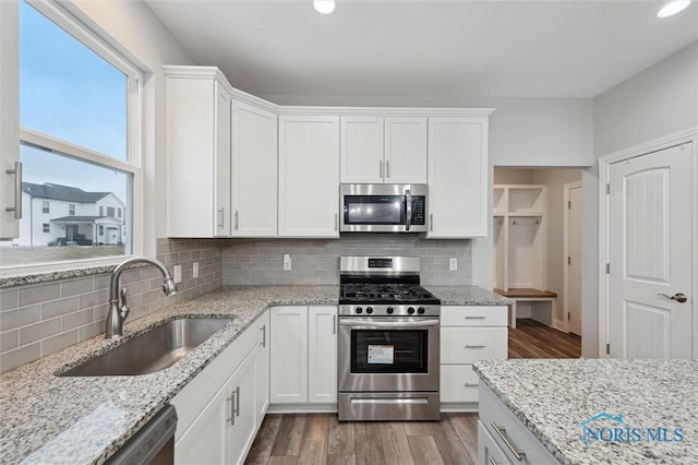 kitchen with stainless steel appliances, sink, wood-type flooring, and white cabinets