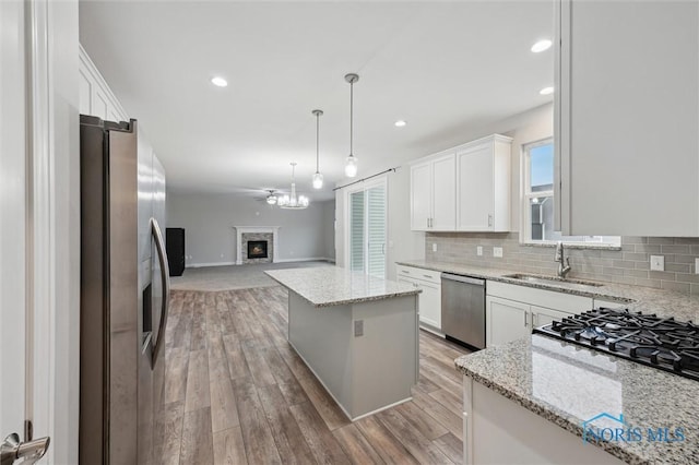 kitchen featuring light stone countertops, stainless steel appliances, a center island, and white cabinets