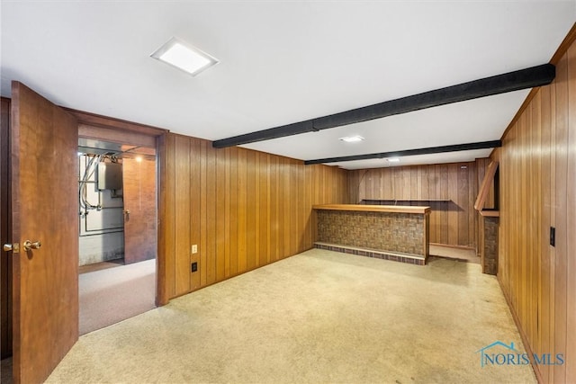 basement featuring light carpet, bar, and wood walls