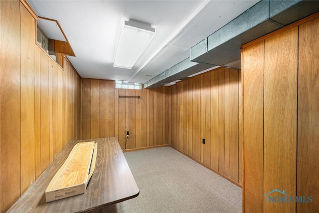 basement featuring wooden walls and light carpet