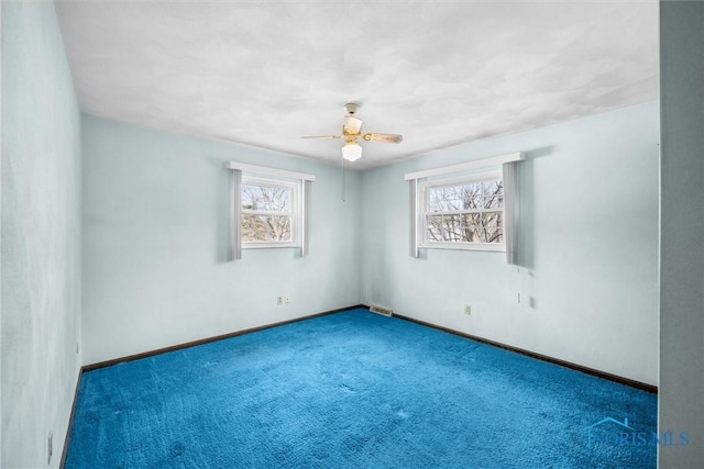 carpeted spare room featuring plenty of natural light and ceiling fan