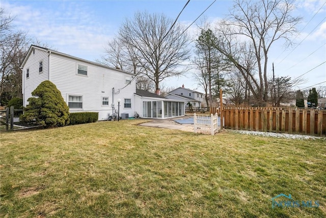 rear view of house featuring a sunroom, central AC unit, a patio, and a lawn