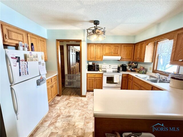 kitchen with white appliances, sink, a textured ceiling, and kitchen peninsula