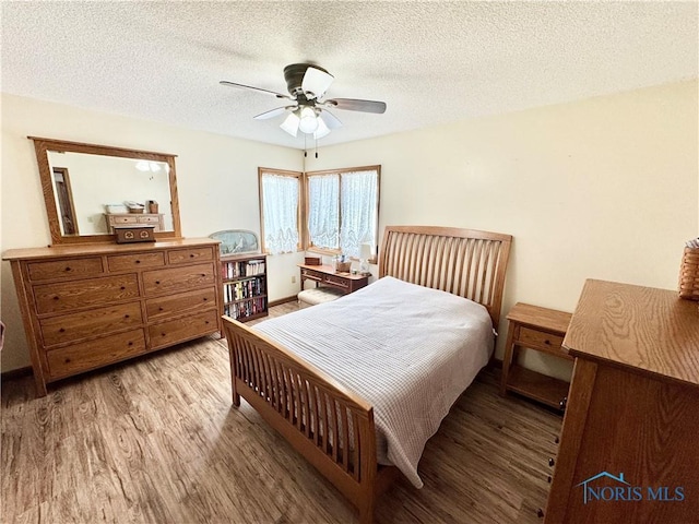 bedroom with light wood-type flooring, a textured ceiling, and ceiling fan