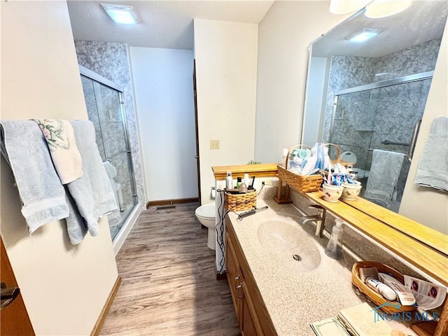 bathroom with wood-type flooring, vanity, toilet, and a shower with shower door