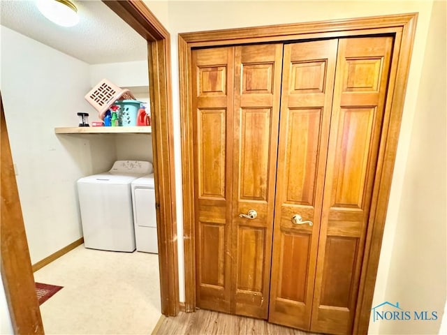 laundry area with light hardwood / wood-style floors, a textured ceiling, and washing machine and clothes dryer