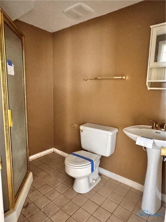 bathroom with a shower with door, tile patterned floors, and toilet