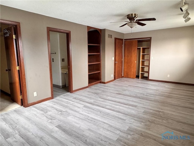 unfurnished bedroom featuring connected bathroom, a closet, a textured ceiling, and light wood-type flooring