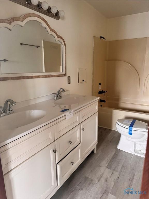 full bathroom featuring vanity, wood-type flooring, shower / bathtub combination, and toilet