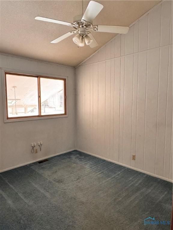 spare room with vaulted ceiling, ceiling fan, dark carpet, and a textured ceiling