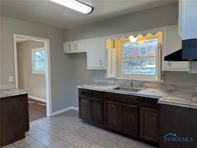 kitchen with white cabinetry, sink, dark brown cabinets, and light tile patterned floors