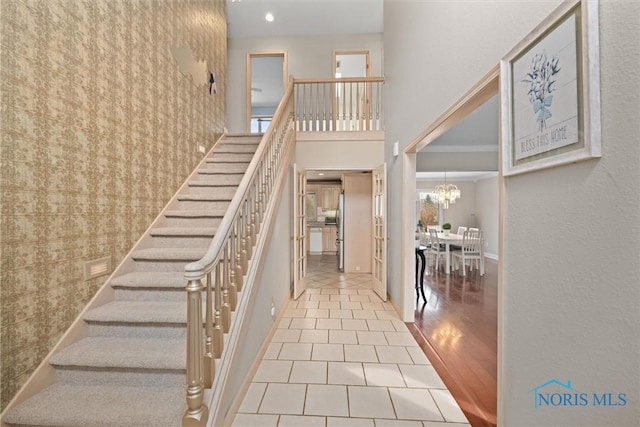 stairs featuring a notable chandelier, a towering ceiling, and tile patterned floors