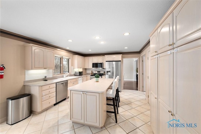 kitchen with crown molding, light tile patterned floors, a kitchen breakfast bar, a kitchen island, and stainless steel appliances