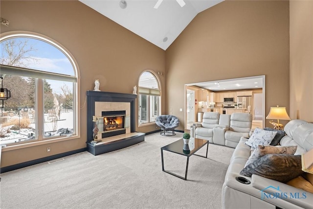 carpeted living room featuring high vaulted ceiling, plenty of natural light, and a tile fireplace