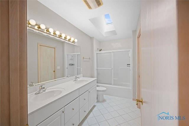 full bathroom with toilet, a skylight, vanity, enclosed tub / shower combo, and tile patterned flooring