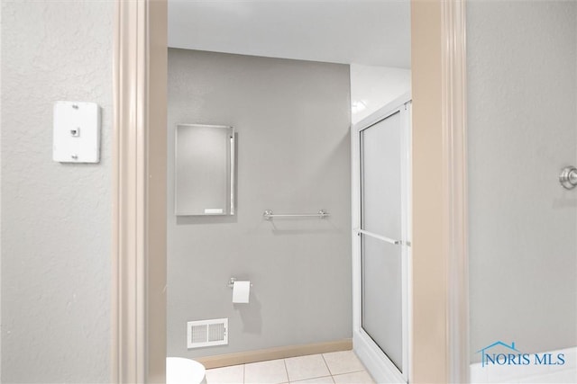 bathroom with tile patterned flooring, toilet, and walk in shower