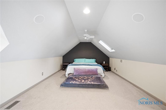 carpeted bedroom with ceiling fan and vaulted ceiling with skylight