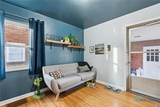 sitting room featuring hardwood / wood-style flooring and brick wall