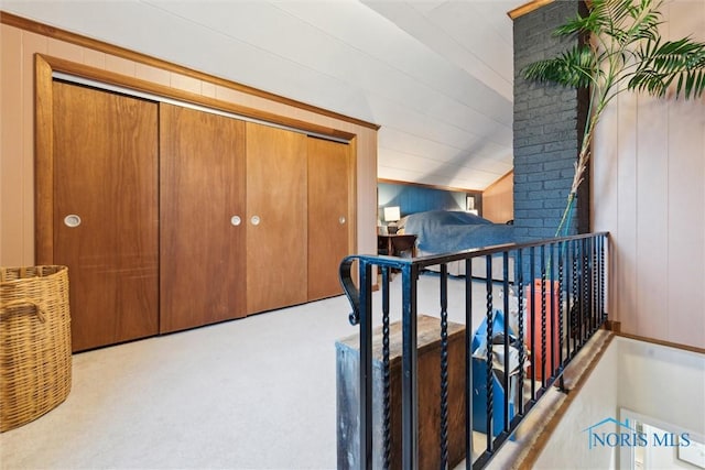 hallway with light colored carpet and wood walls