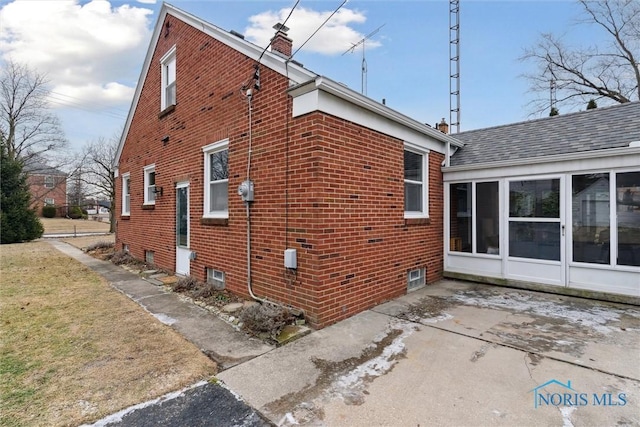 view of side of property featuring a patio area and a sunroom