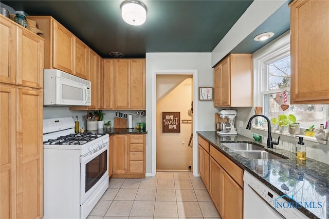 kitchen featuring sink, light brown cabinets, light tile patterned floors, white appliances, and dark stone counters