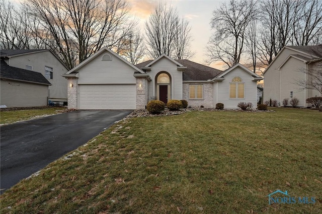 single story home featuring a garage and a yard