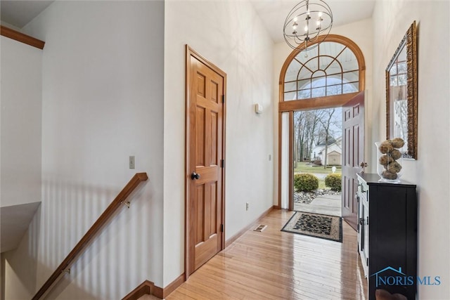 foyer with a high ceiling, a chandelier, and light hardwood / wood-style floors