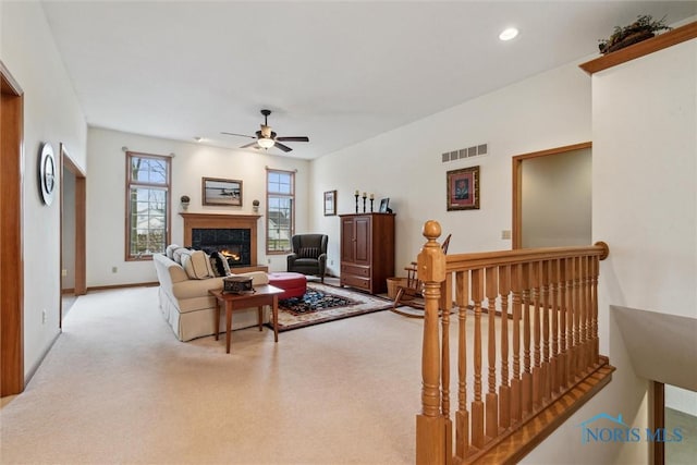 carpeted living room featuring a premium fireplace and ceiling fan