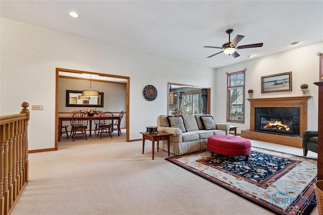 carpeted living room with ceiling fan and a tiled fireplace