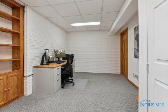 carpeted office space with brick wall and a drop ceiling