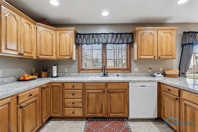 kitchen featuring light stone countertops, sink, and white dishwasher