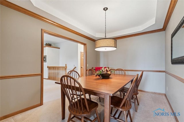 carpeted dining space featuring ornamental molding and a tray ceiling