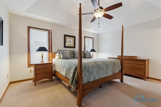 carpeted bedroom featuring a raised ceiling and ceiling fan