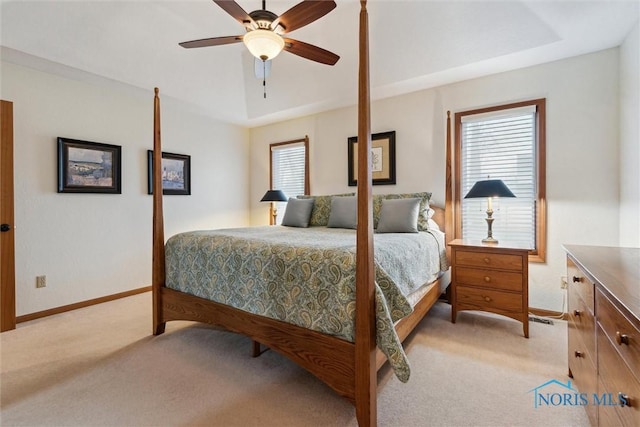 bedroom with light colored carpet, a raised ceiling, and ceiling fan