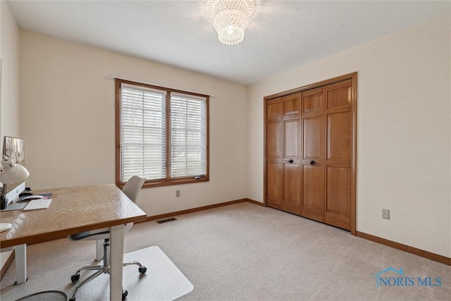 carpeted office space featuring a chandelier