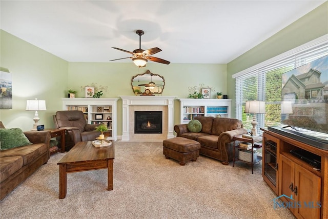 living room featuring a fireplace, light colored carpet, and ceiling fan