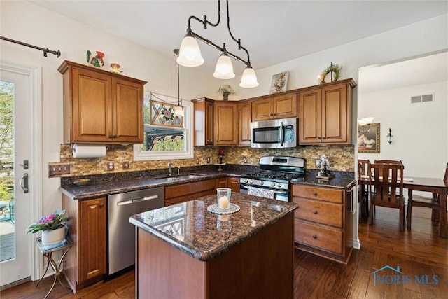 kitchen with sink, a center island, hanging light fixtures, appliances with stainless steel finishes, and a healthy amount of sunlight