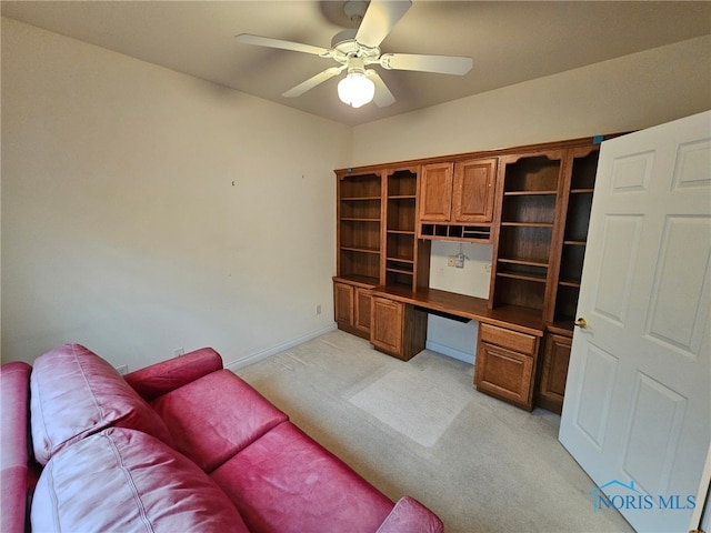 carpeted home office with built in desk and ceiling fan