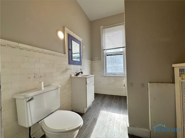 bathroom with vanity, toilet, wood-type flooring, and tile walls