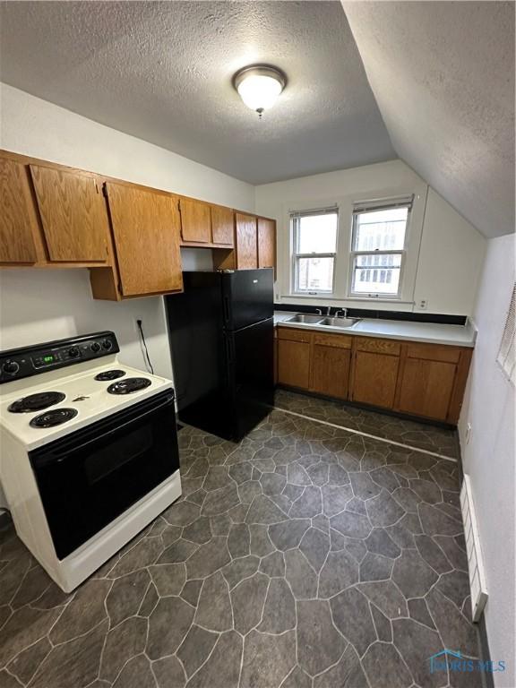 kitchen featuring lofted ceiling, sink, black refrigerator, white range with electric stovetop, and a textured ceiling