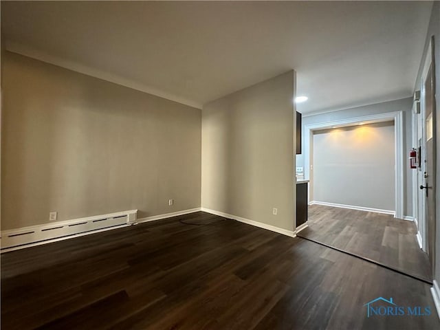 empty room with baseboard heating and dark hardwood / wood-style flooring