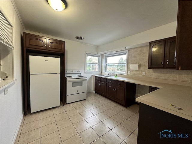 kitchen with dark brown cabinetry, sink, light tile patterned floors, white appliances, and decorative backsplash